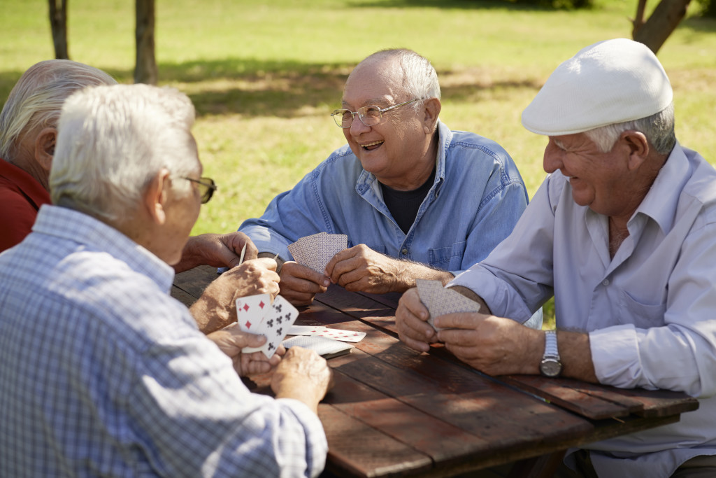 Active seniors, group of old friends playing cards at park